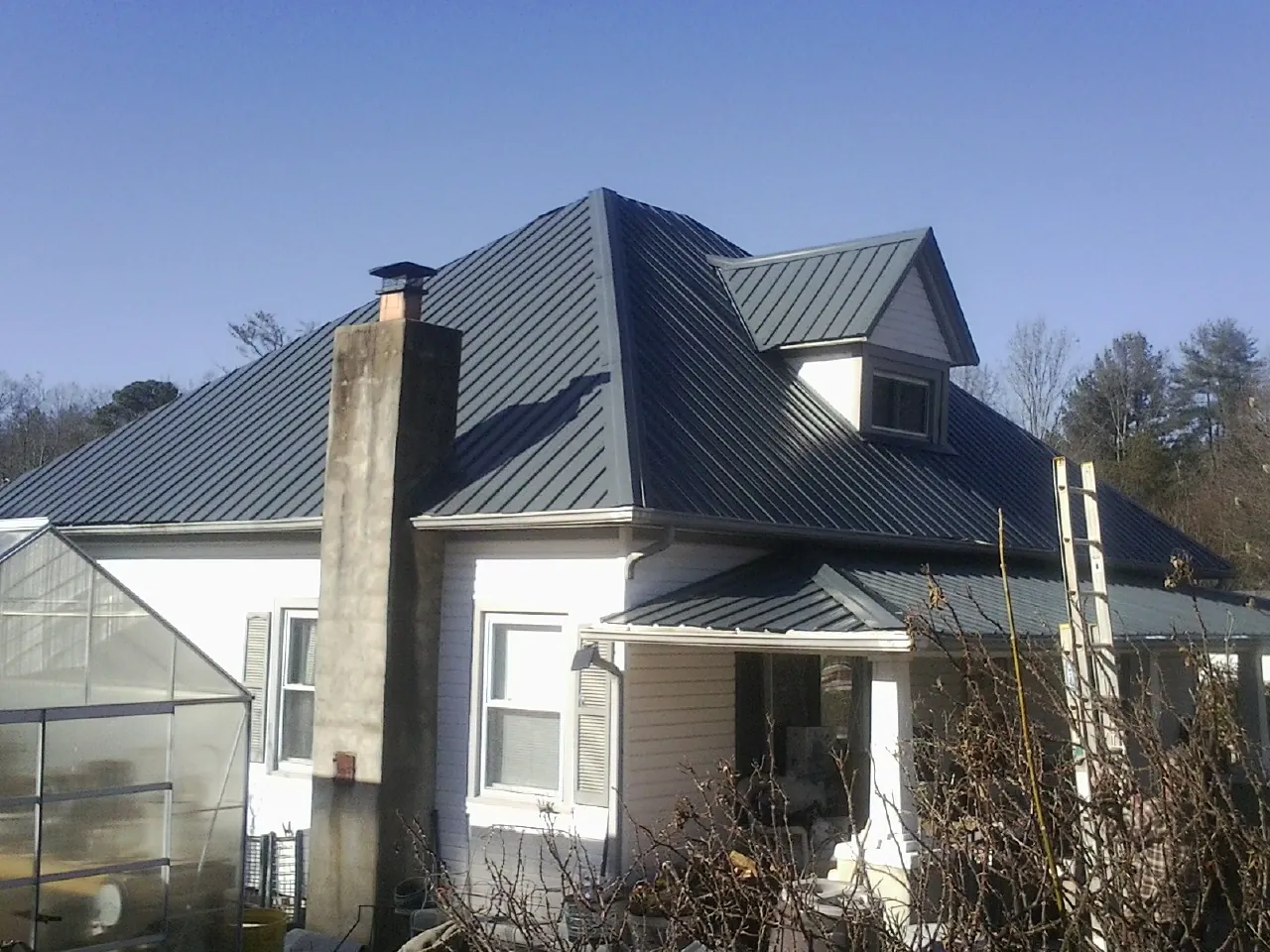 Dark blue standing seam metal roof on a white farmhouse with dormer — Slate & Tile Roof Repair by Roofing Brothers in Kerman