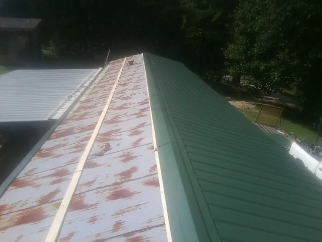 Old rusted panels beside newly installed green metal roofing — Wind Damage Roof Repair by Roofing Brothers in Kerman