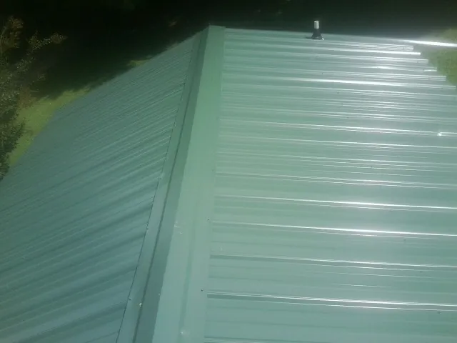 New green metal panels meeting at the ridge of a roof — Flat Roof Repair work by our crew in Kerman