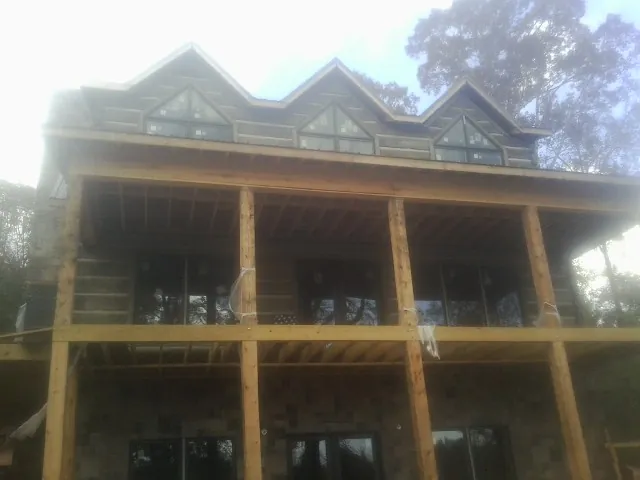 Dormers and porch framing on a large log home under construction — Roof Coating work by our crew in Kerman