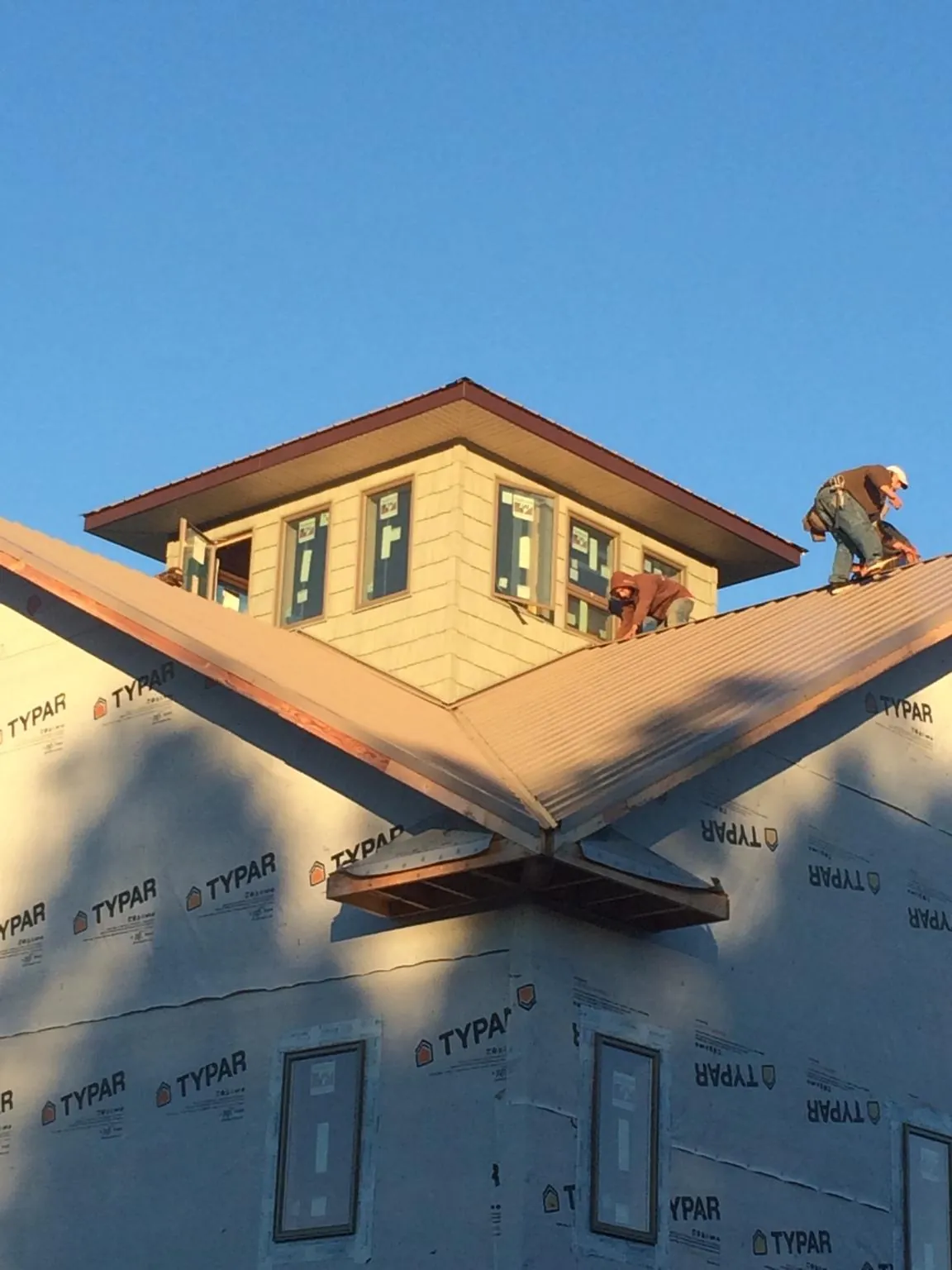 Roofers working around a rooftop cupola on a new metal roof at sunset — Roof Waterproofing in Kerman by Roofing Brothers